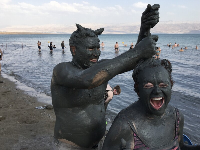 Jill Gleeson and a friend covered in black sand at the Dead Sea, Israel